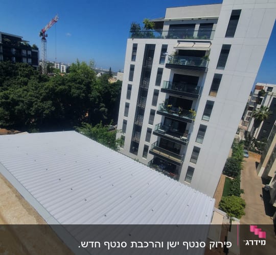 בניין מגורים עם גג מתכת לבן ועגורן ברקע